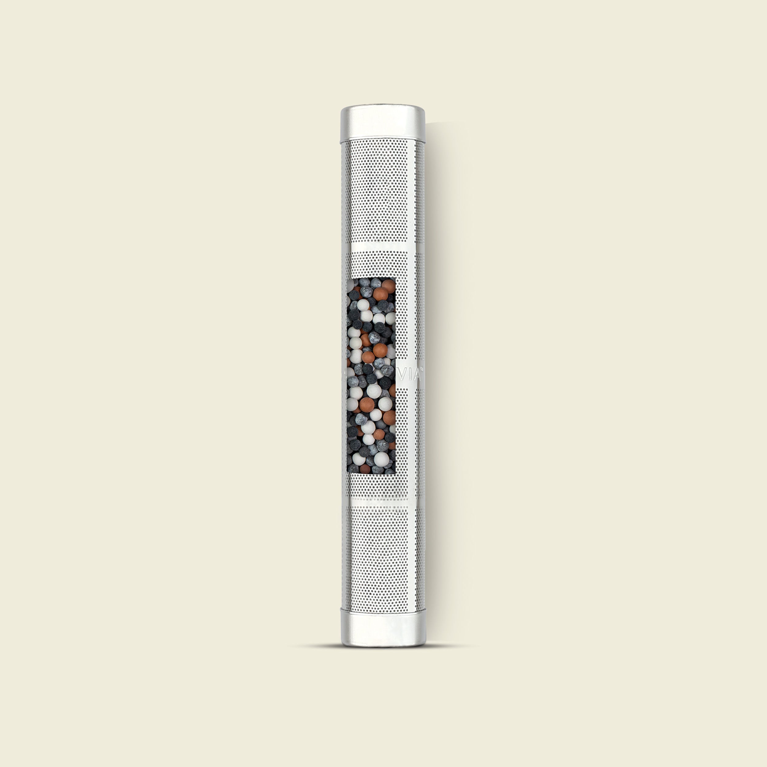 Metallic water filter with black and red filtration media on a beige background